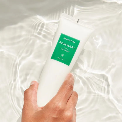 Hand holding a tube of Aromatica Rosemary 2-in-1 Treatment on a white background
