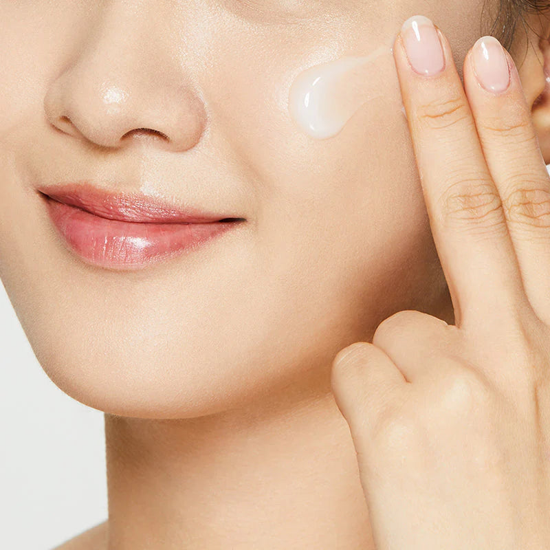 Model applying COSRX Snail 92 Cream for hydrated glowing skin and skin barrier strengthening skincare routine