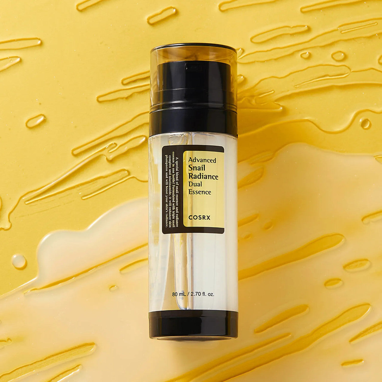 COSRX Advanced Snail Radiance Dual Essence serum bottle with snail mucin essence texture on yellow background