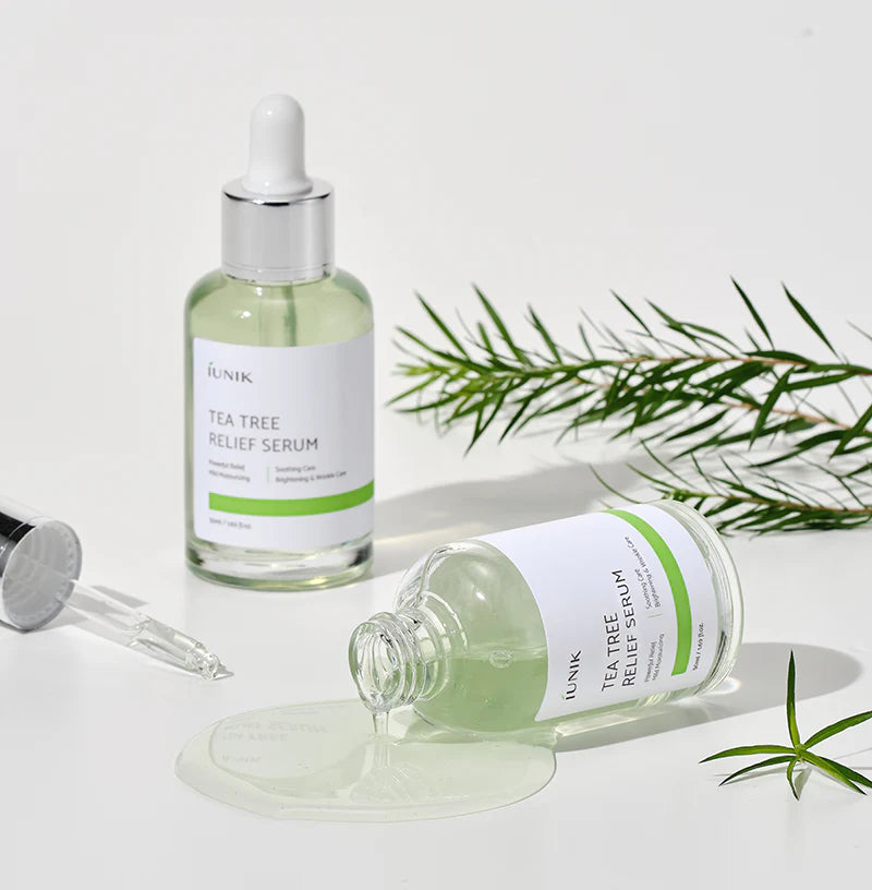 iUNIK Tea Tree Relief Serum dropper releasing a drop beside fresh tea tree sprigs