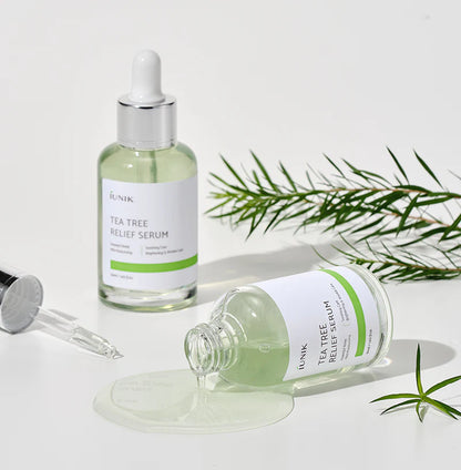 iUNIK Tea Tree Relief Serum dropper releasing a drop beside fresh tea tree sprigs
