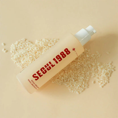 K-Secret Seoul 1988 Snail Mucin Essence bottle with scattered rice grains showcasing the key ingredient