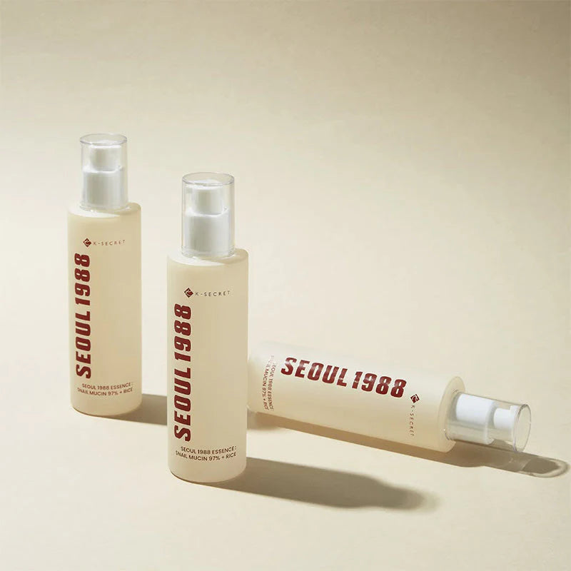 Two K-Secret Seoul 1988 Snail Mucin Essence bottles standing on a beige background, Korean skincare in Jeddah