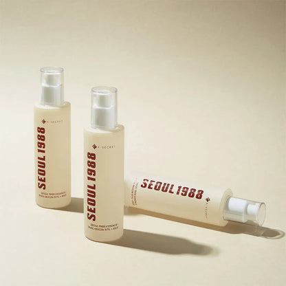Two K-Secret Seoul 1988 Snail Mucin Essence bottles standing on a beige background, Korean skincare in Jeddah