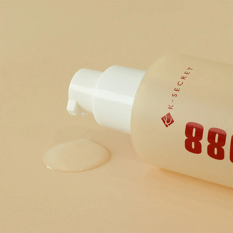 K-Secret Seoul 1988 Snail Mucin Essence bottle lying beside a clear essence swatch on a beige background