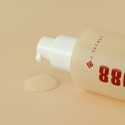 K-Secret Seoul 1988 Snail Mucin Essence bottle lying beside a clear essence swatch on a beige background